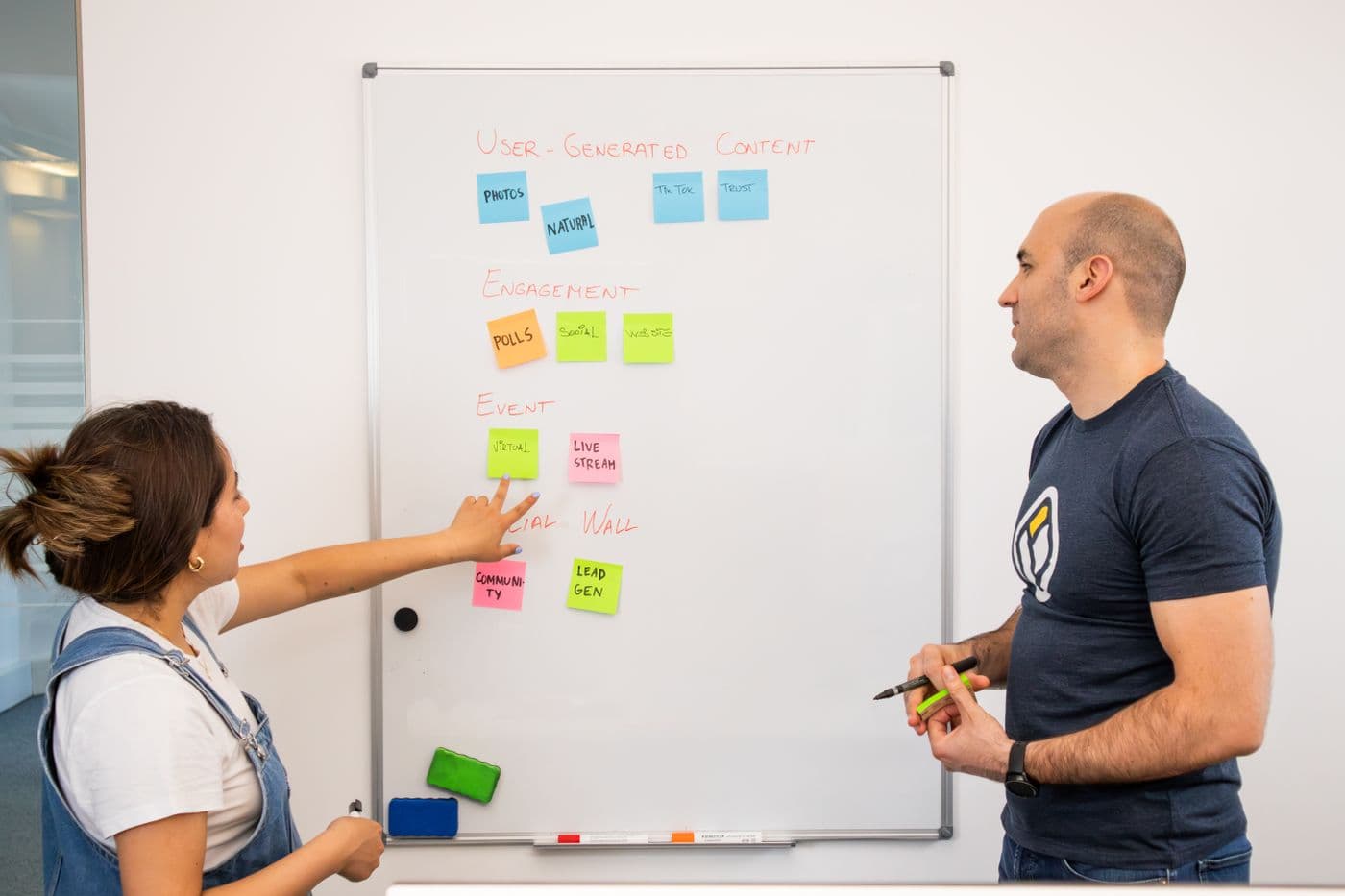Colleagues sharing ideas beside a whiteboard