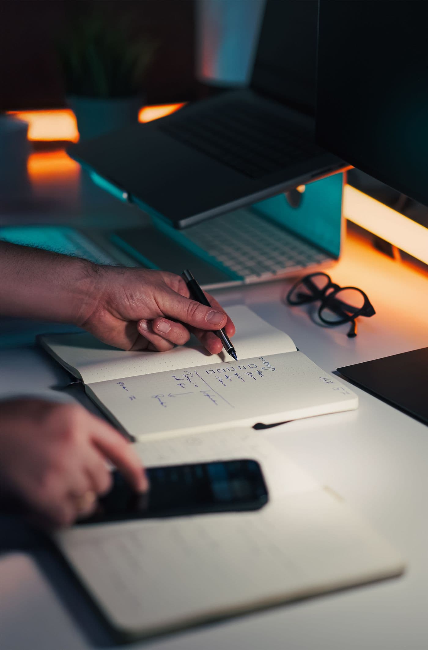 Hands writing review notes at an office desk